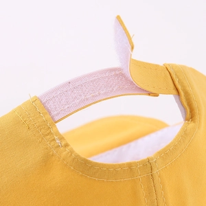 Detail of adjustable hook and loop closure on yellow cartoon baseball cap for toddlers