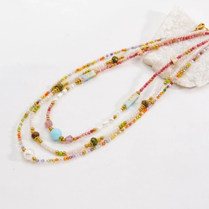 Multilayer beaded necklace with pearls and colorful stones on a white background
