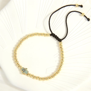 Macro detail of Hamsa Hand charm with blue crystals on gold beaded adjustable bracelet