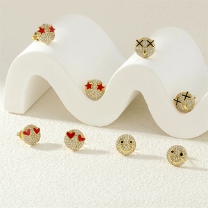 Detailed view of gold smiley face earrings with sparkling crystals and enamel details