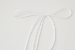 Detailed view of elegant white fabric tie waist belt tied in a neat bow knot on dress