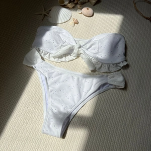 Detailed view of white eyelet embroidery bikini set with ruffles and seashell props
