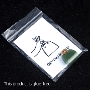 Green crystal bag-shaped pendant on card in clear pouch with gold metal clasp