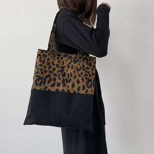 Detail of leopard print canvas tote bag on model shoulder with minimalist black拼接 design