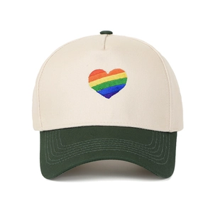 Dettaglio ravvicinato del ricamo cuore arcobaleno vivace su un cappellino bicolore