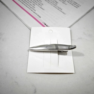 Close-up of polished silver alloy hair clip with curved design on a white display card