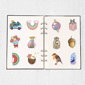 Detail of waterproof cartoon stickers showing camping van and rainbow on a white notebook