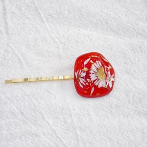 Handmade red resin hair clip with dried white flowers and gold leaf foil detail