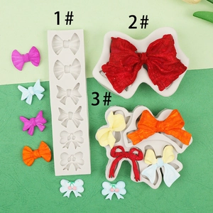 Detailed view of three silicone bow molds with colorful fondant and resin shapes