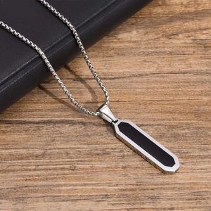 Detailed view of men's geometric pendant with silver frame and black inlay on a steel box chain