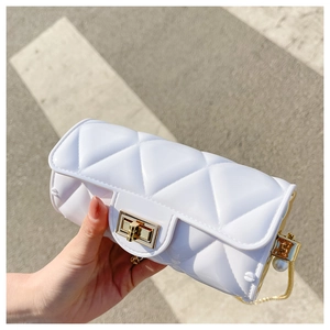 Detail of white quilted jelly bag with golden lock and decorative pearl chain strap