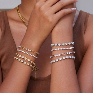 Close-up of elegant gold and silver bracelets with zircons worn together by a model