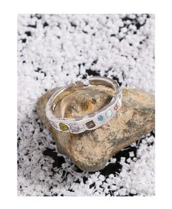 Macro shot of S925 silver ring with wrinkled texture and colorful zircon on natural stone
