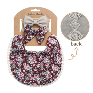Detail of floral baby bib and headbands set with lace trim on cardboard display