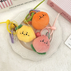 Vue détaillée des porte-clés en peluche fruits citron, orange et pêche sur une assiette
