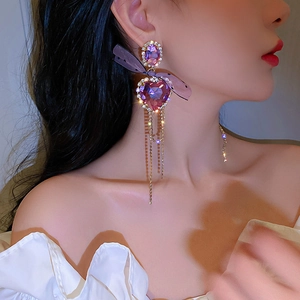 Detail of purple heart crystal earring with polka dot bow and rhinestone tassels on model