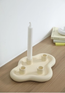 Détail d'un bougeoir en céramique crème avec des bords ondulés et quatre fentes pour bougies