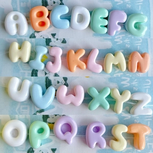 Macro shot of 26 colorful macaron-style alphabet resin beads for DIY jewelry making