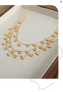 Detailed view of triple-layered gold shell necklaces with zircon stones on velvet