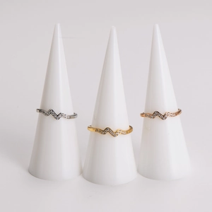 Macro detail of wave-shaped rings with pave-set crystals in gold, silver, and rose gold