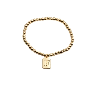 Détail de bracelet à perles plaqué or avec pendentif rectangulaire gravé de la lettre F