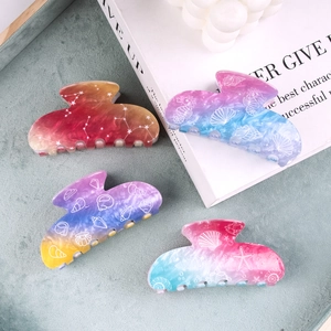 Set of 4 colorful gradient hair claws with shell and star patterns on a tray