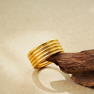 Minimalistischer mehrlagiger 18K Goldring mit glatter Textur auf einem Holzuntergrund