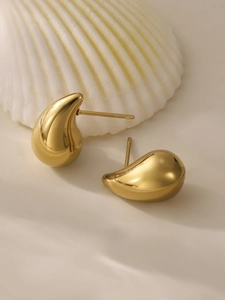 Detailed close-up of 18k gold-plated stainless steel teardrop earrings on a cream background