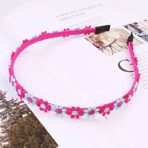 Close-up of pink woven headband with blue flower embroidery on an open magazine