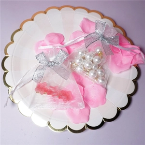 Close-up of a white organza jewelry bag with silver bow and pearl accents in a tray