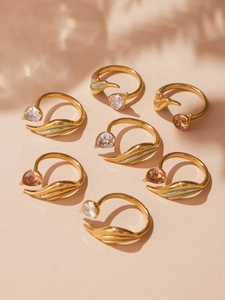 Detailed close-up of gold stainless steel rings with zircon droplets and blue enamel wings
