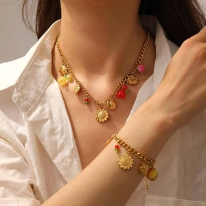 Détails de l'ensemble collier et bracelet dorés avec breloques fleurs et fruits colorés