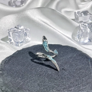 Close-up of a silver snake open ring with blue stone accents on a dark stone and silk background