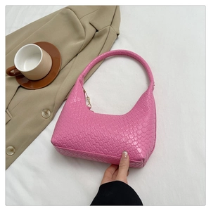 Close-up showing the woven texture and bottom detail of a pink shoulder bag with gold chain
