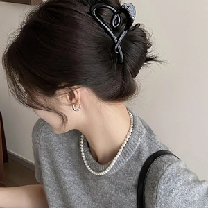 Pince à cheveux noire élégante en forme de cœur présentée dans un chignon avec perles