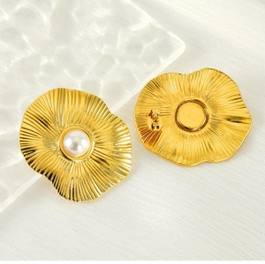 Vue détaillée de l'incrustation de perles et texture pétale sur boucles en acier doré 18k