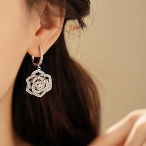 Detailed view of silver rose earrings with cubic zirconia pavé on an elegant model