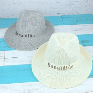 Detail of woven straw sun hats in grey and beige with decorative Ronaldino ribbons