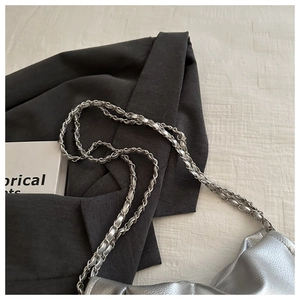 Close-up of silver braided metal chain strap on casual pleated cloud shoulder bag