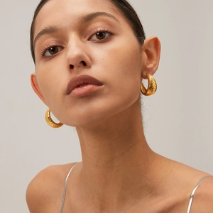 Close-up of model wearing 18k gold stainless steel hoop earrings with fish scale texture