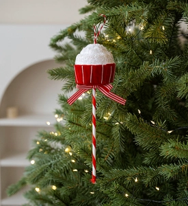 Close-up of red and white velvet cupcake Christmas ornament on a lighted tree