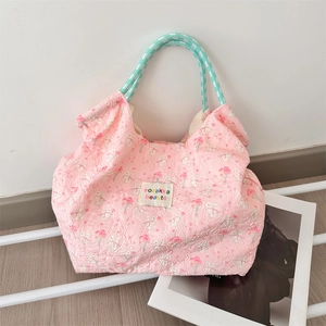 Detailed texture of pink quilted tote bag with rabbit floral print and knotted rope handles