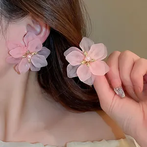 Floral stud earrings with pink layered petals and pearl center shown on a female model
