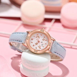 Détail de montre or rose avec cadran lune étoile et bracelet en cuir bleu fille