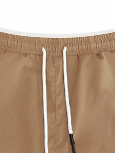 Detail of khaki cargo pants featuring an elastic waist with white drawstring and metal tips