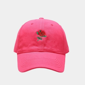 Dettaglio del ricamo a rosa rossa su un cappellino da baseball in cotone rosa acceso