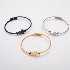 Three steel cable cross bracelets in gold, silver, and black finishes on white background