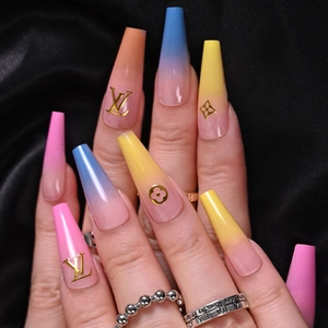 Macro shot of long coffin fake nails featuring colorful gradient and golden luxury patterns