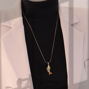 Détail d'un collier long vintage avec pendentif carpe koi et chaîne serpent dorée