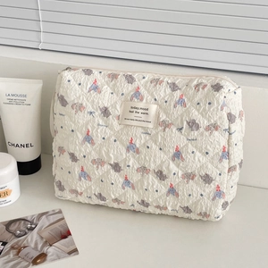 Detail of quilted white makeup bag with cute blue elephant prints and zipper closure